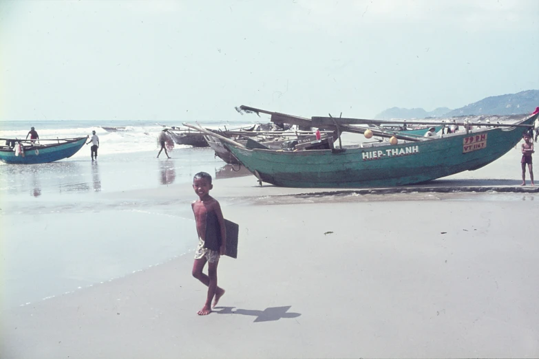 a man stands on the beach with two boats in the background