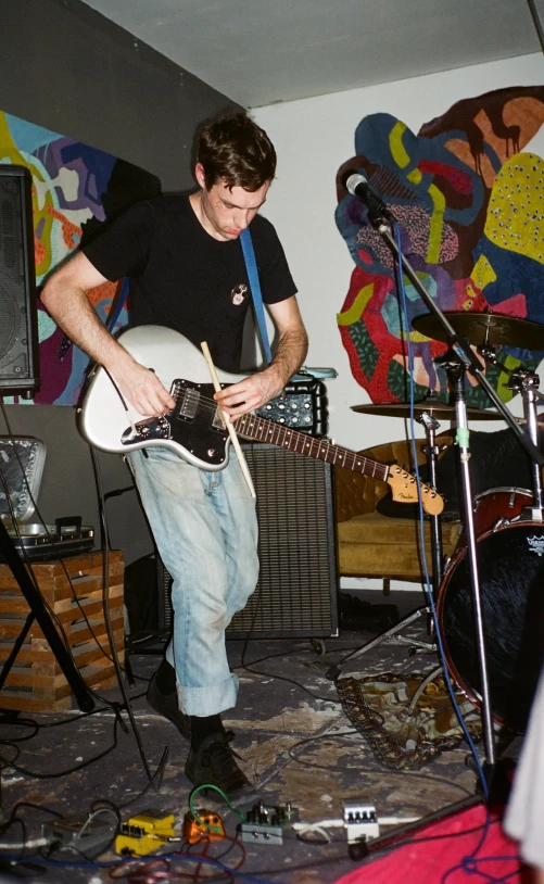 a man with an electric guitar standing next to a speaker and a guitar