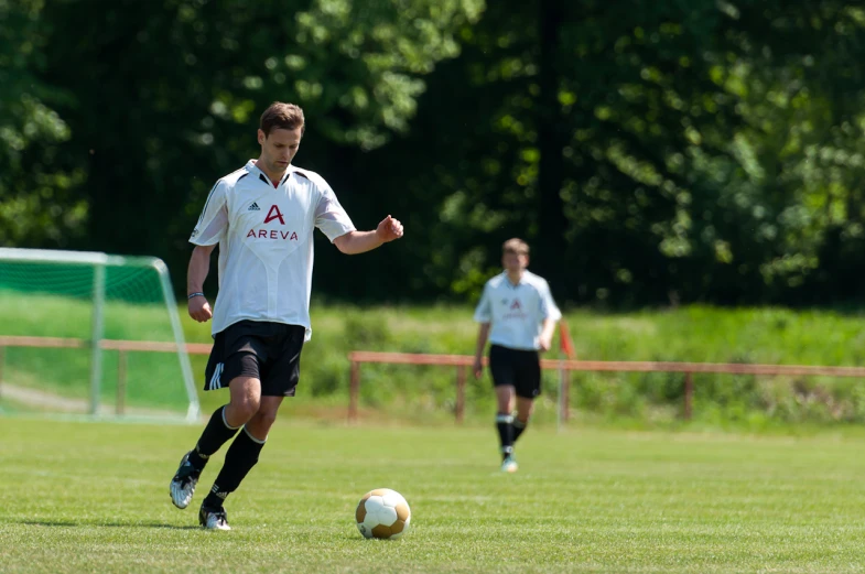 two soccer players kicking ball across a field