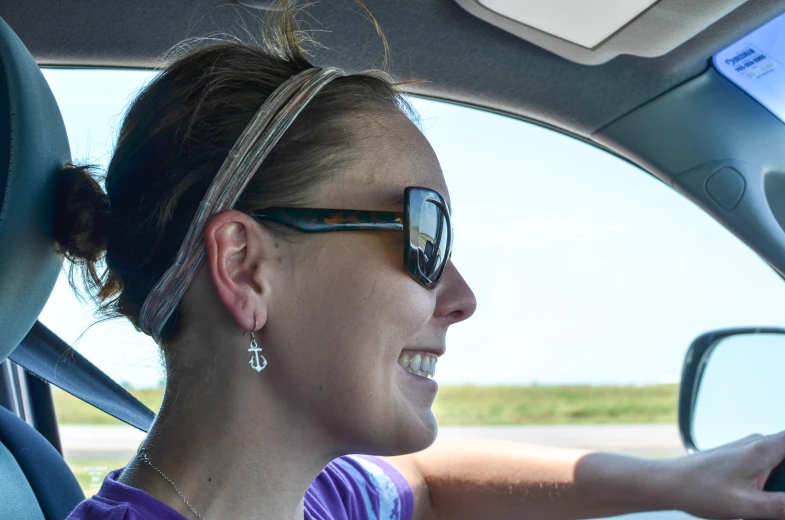 a woman smiling and sitting in a car with her cell phone