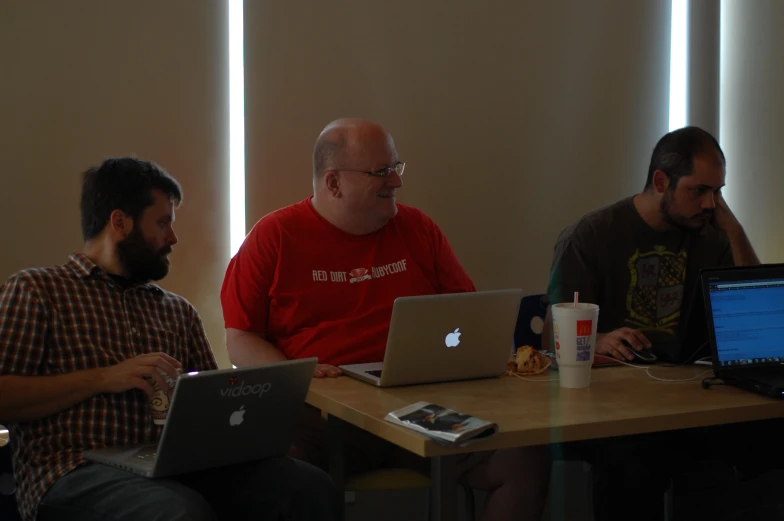 three men sit at a table in a room