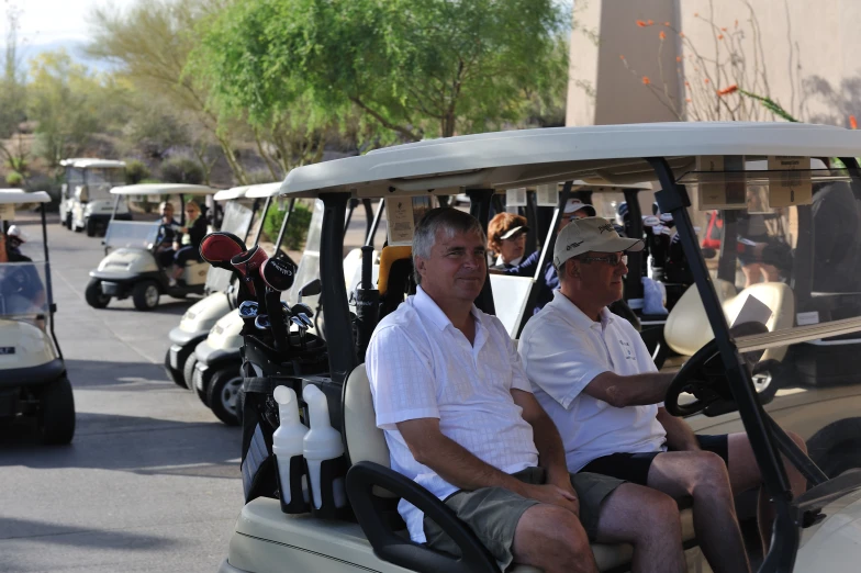 two men in golf carts with helmets, driving down the street