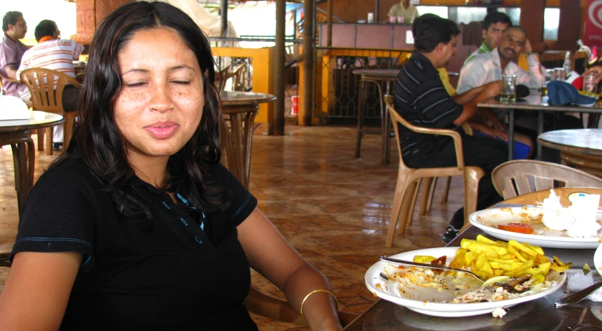 the woman sits at a restaurant with food on plates