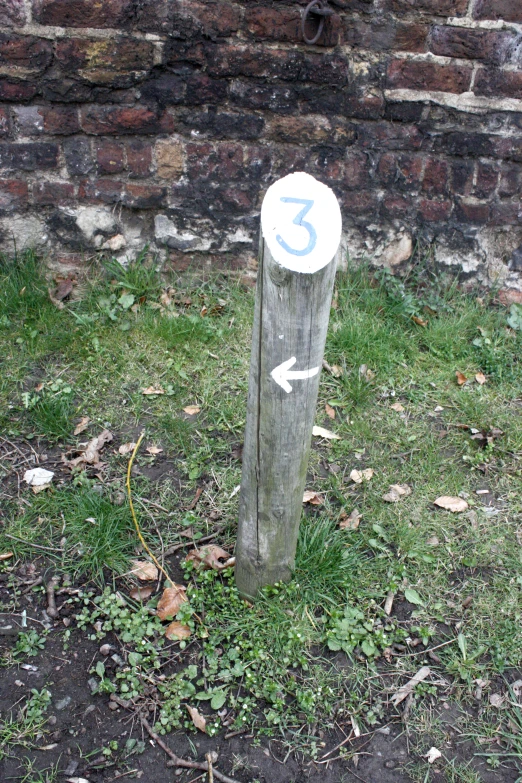 a pole that has an arrow and a white sign on it