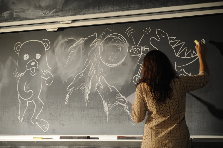 a woman writing on the blackboard with chalk