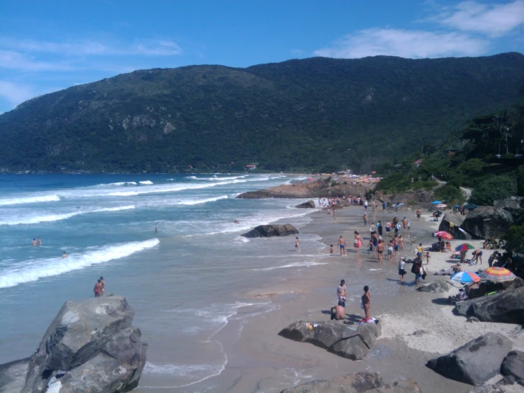 beach with people and rocks near water in daytime