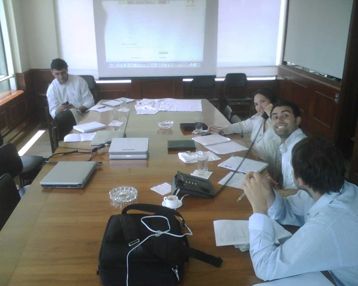 a group of people in a room with desk and laptop