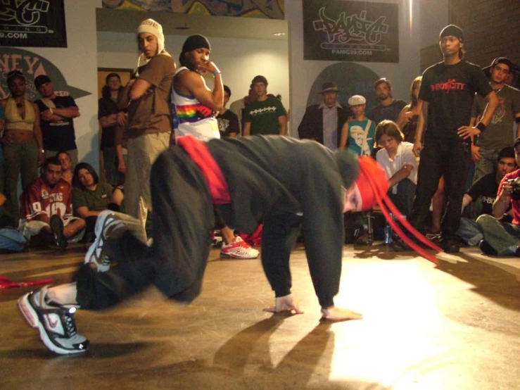 a crowd of young people watching a young man dance on the floor