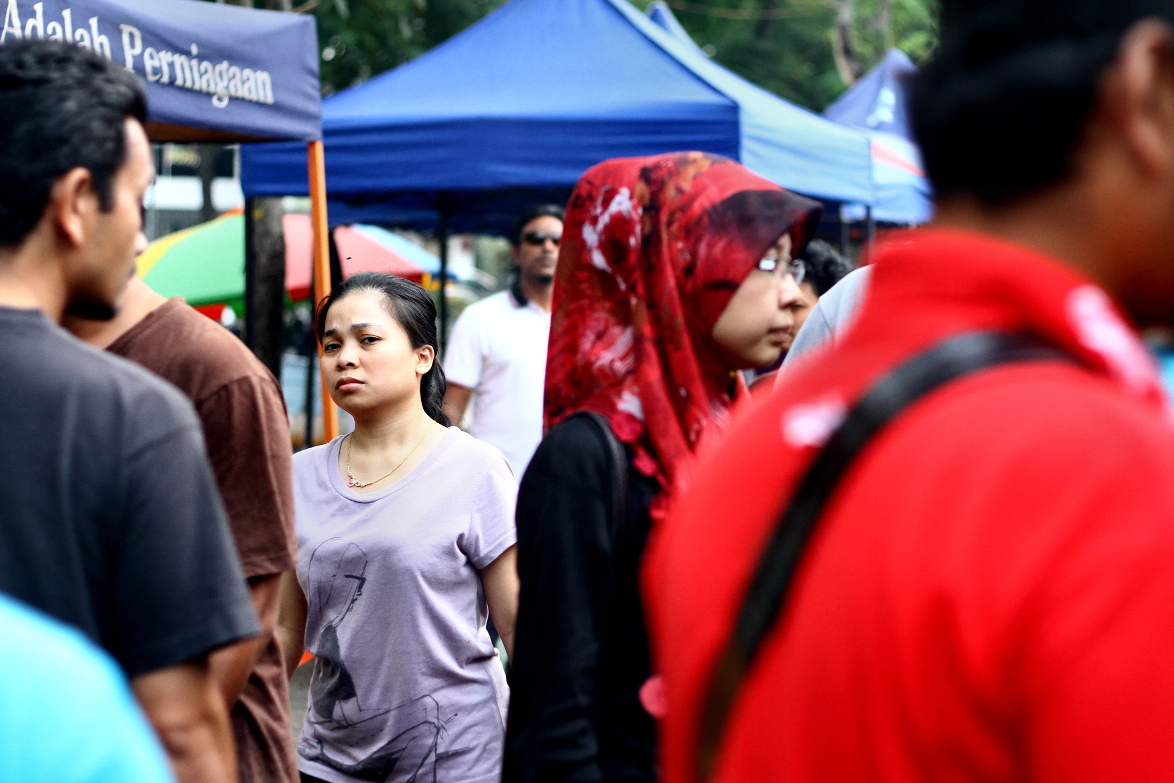 several people walking around in a crowd near booths