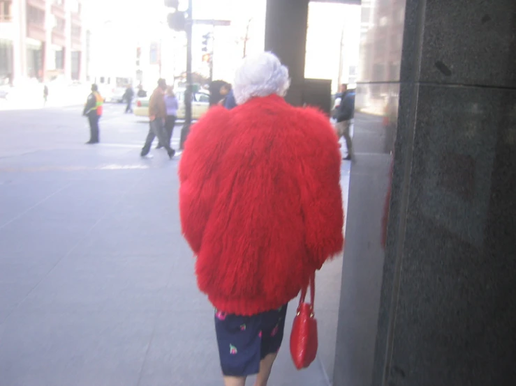 a woman in a fuzzy coat walking on a street