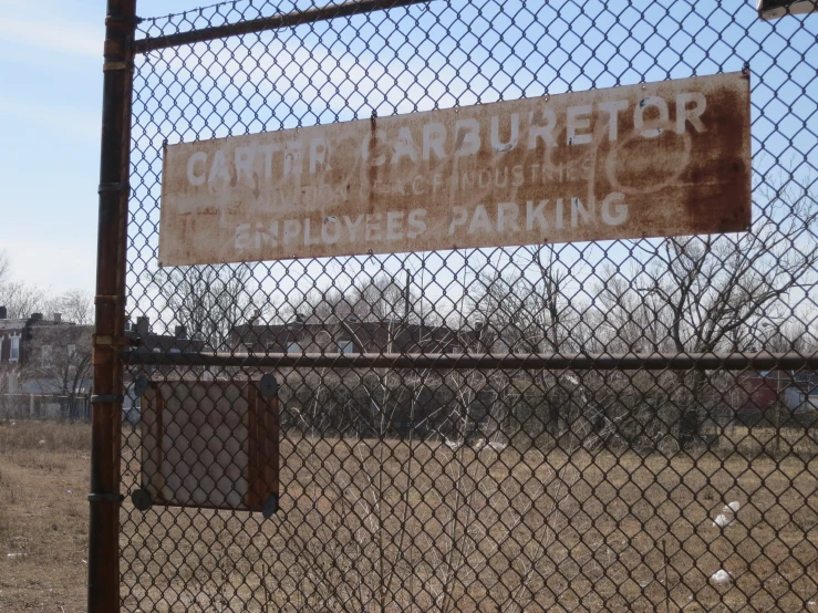 a brown sign on a chain link fence