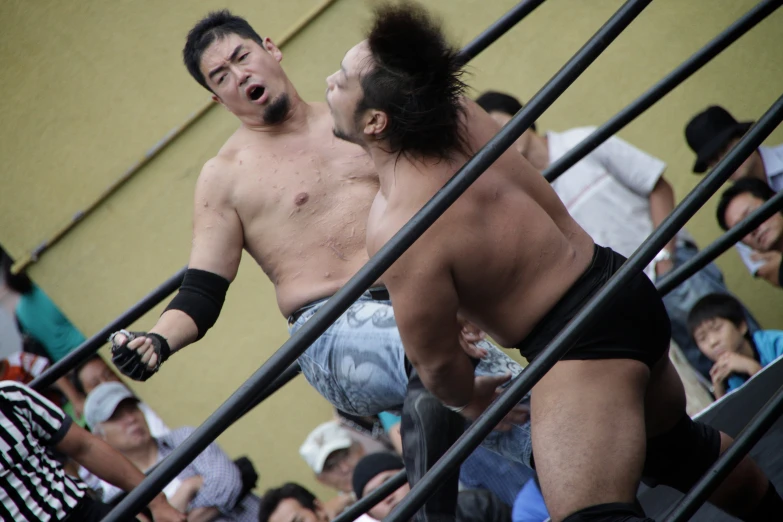 two men wrestling with people behind them