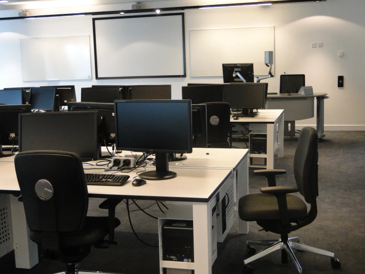 an empty office with many monitors, keyboards and desks