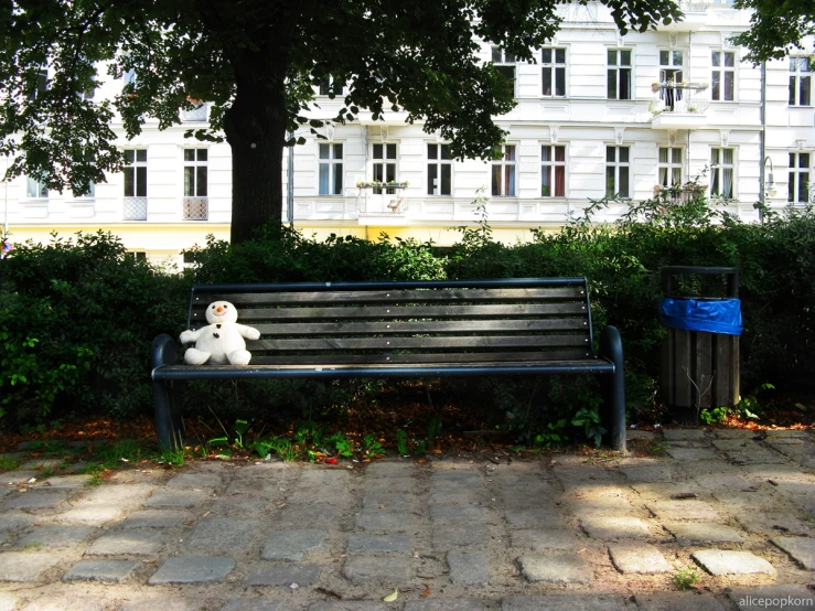 a bench with a stuffed animal on it sitting in a park