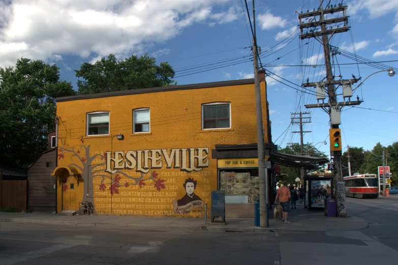 the corner shop features a large, yellow building with a large mural painted on it