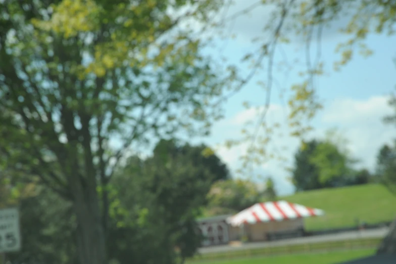 a field is shown with trees and a red white and blue striped tent