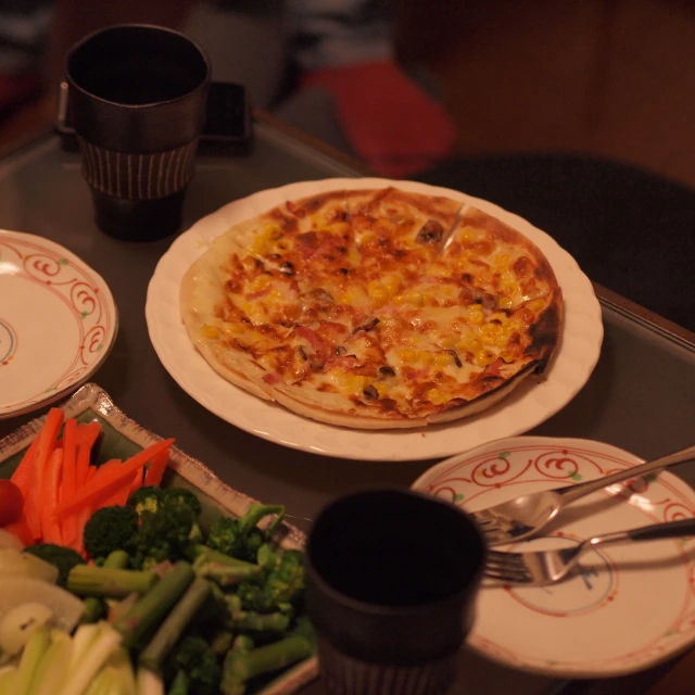 a plate of pizza and some carrots and broccoli on a table