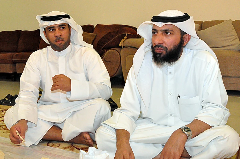 two men dressed in white sitting on the floor