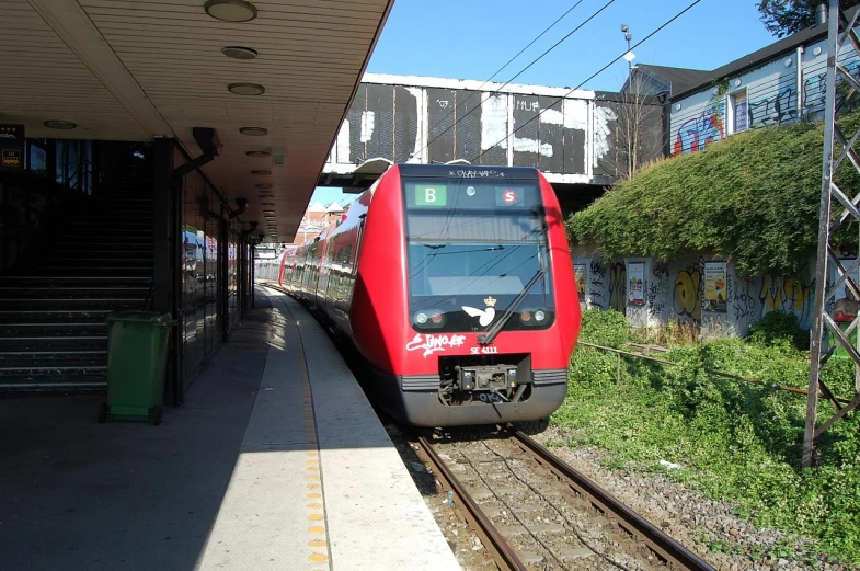 an empty train station with a red train stopped