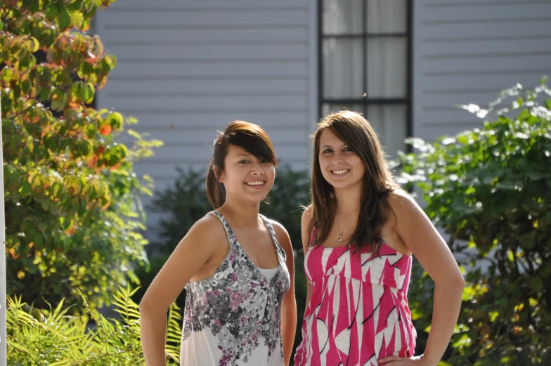 two young women standing next to each other outside