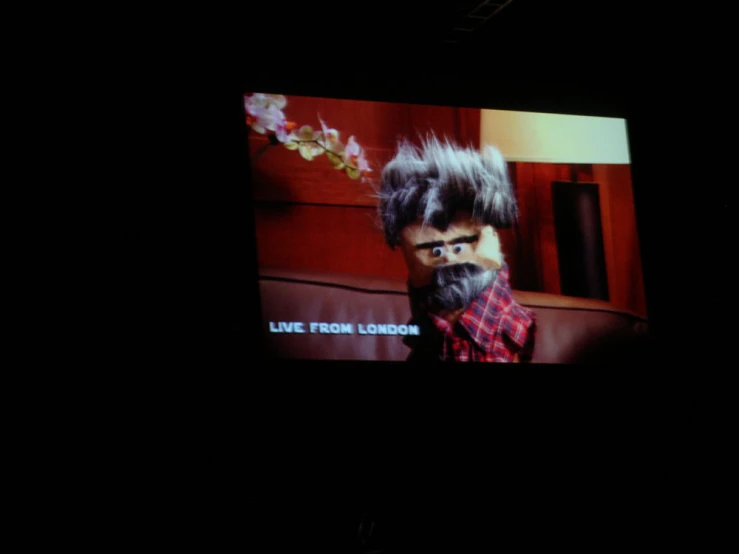 man looking at his hair in a television screen