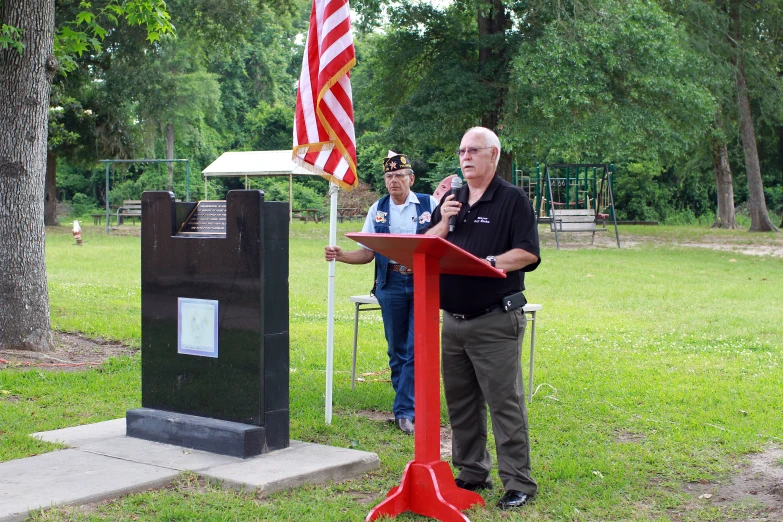 a man stands next to a red marker in the grass