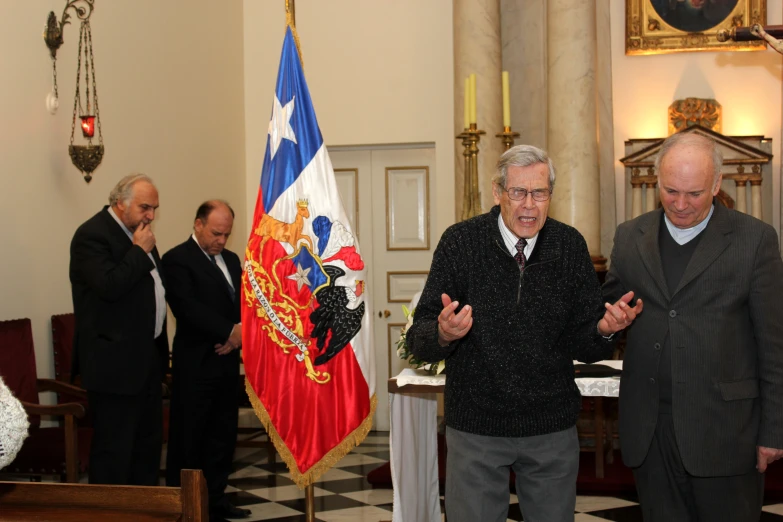 two men shaking hands while a group of other people stand around