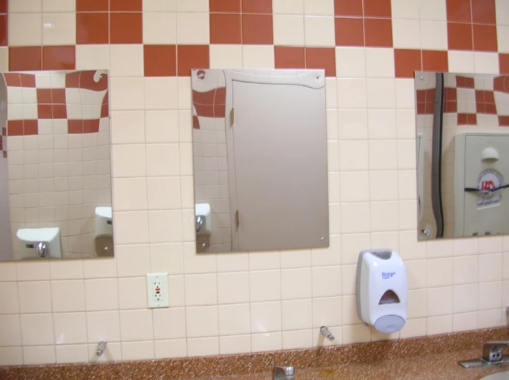 three mirrors on a bathroom wall one has a urinal and two are mirrors
