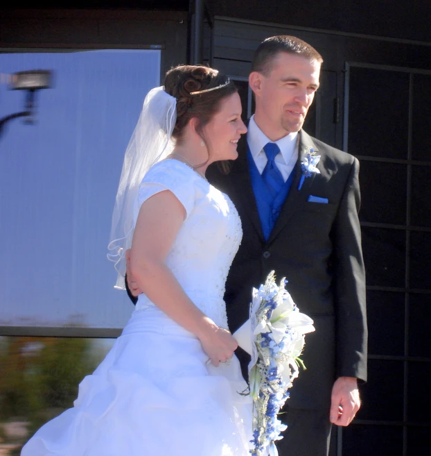 a bride and groom stand outside of their venue