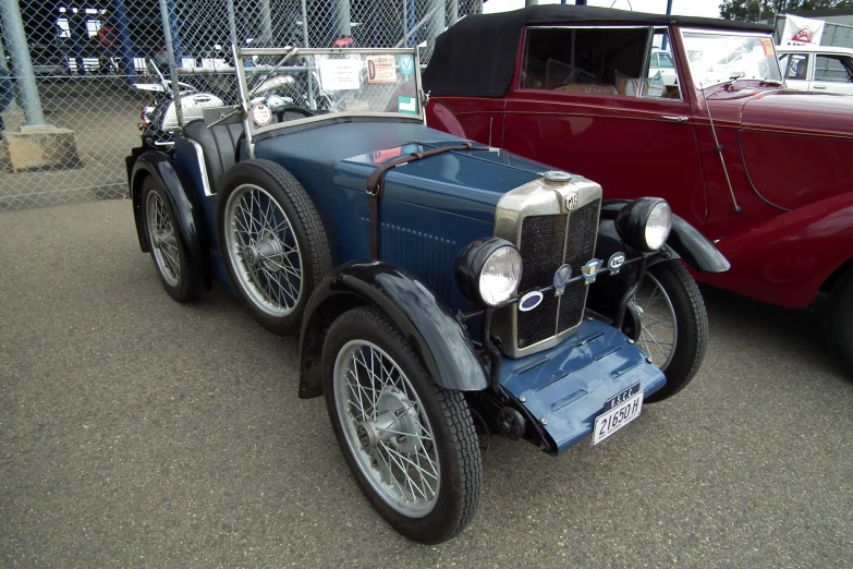 a red old car and an older car in a parking lot