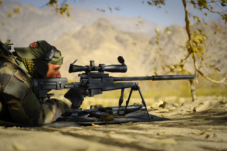 an armed soldier, holding a rifle and aiming