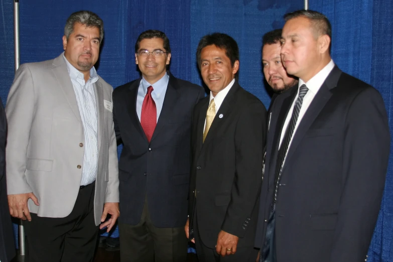 some men standing up in front of a blue curtain