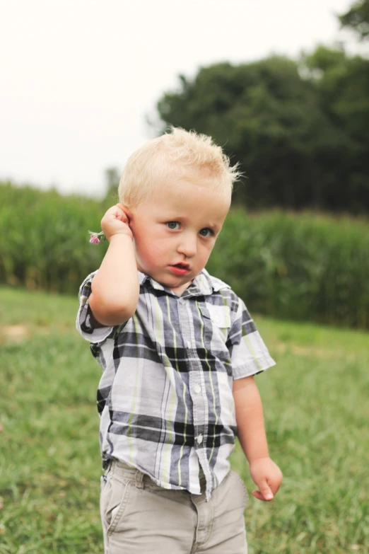 a little boy holding his hand up to his ear