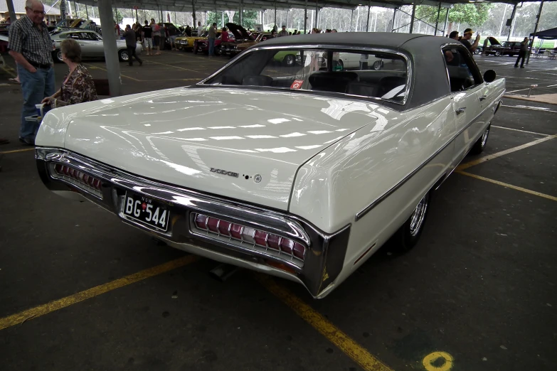 a classic car sits parked in a car park with its hood up