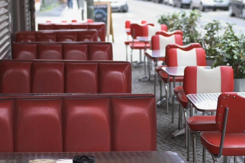 many red chairs line a street with a restaurant