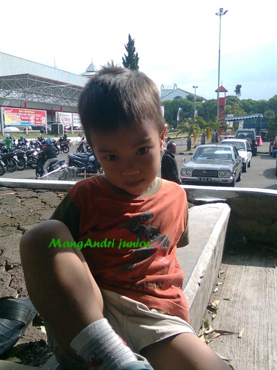 a little boy sitting on a bench in the street