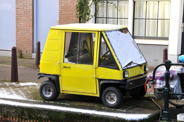 a yellow electric three wheeled vehicle parked on the side of a street