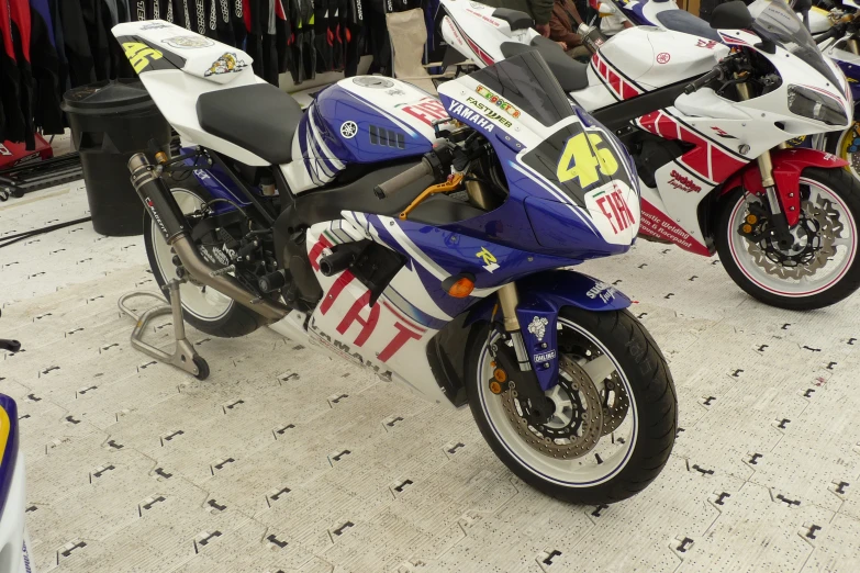 motorcycles lined up in a shop with man and woman behind them