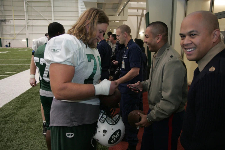 a woman is shaking hands with football players on a field