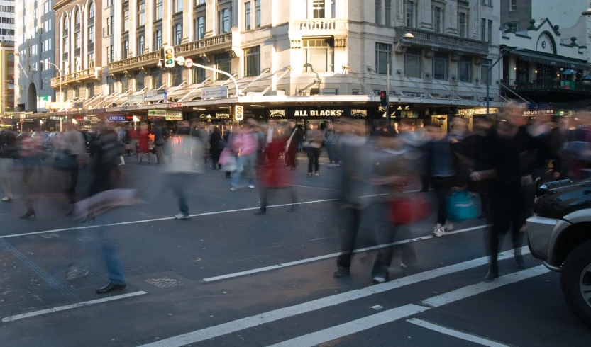 a busy city street at sunset with a group of people walking and talking