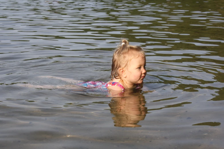 a girl swimming in the water with her hands behind her head