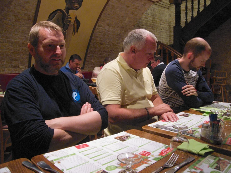 a group of men sitting at a table with forks and utensils