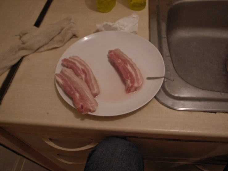 two bacon strips sitting on top of a plate next to a silver sink