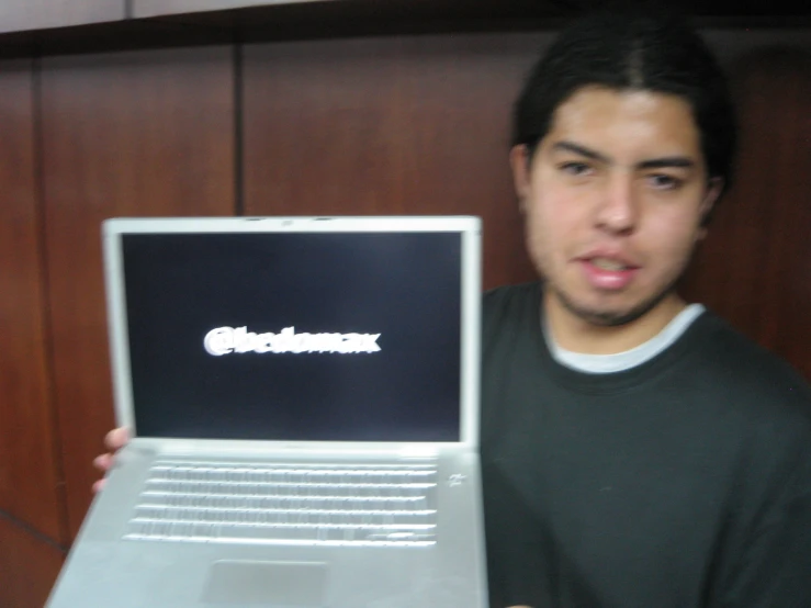 a man holding up an open silver laptop