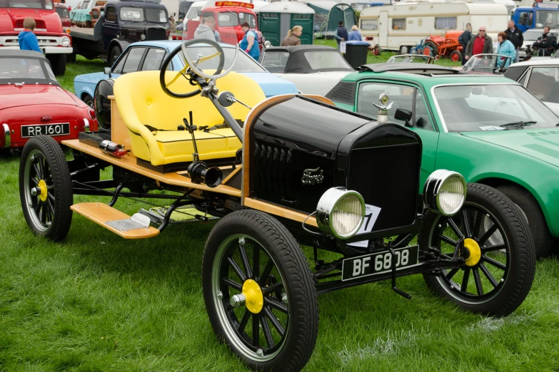 a yellow old time car on display at a classic automobile show