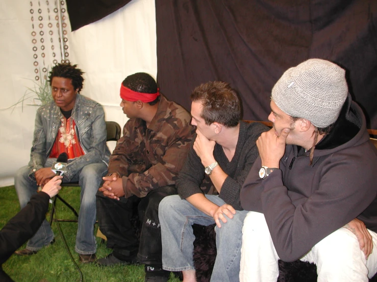 three young men are sitting on a green lawn