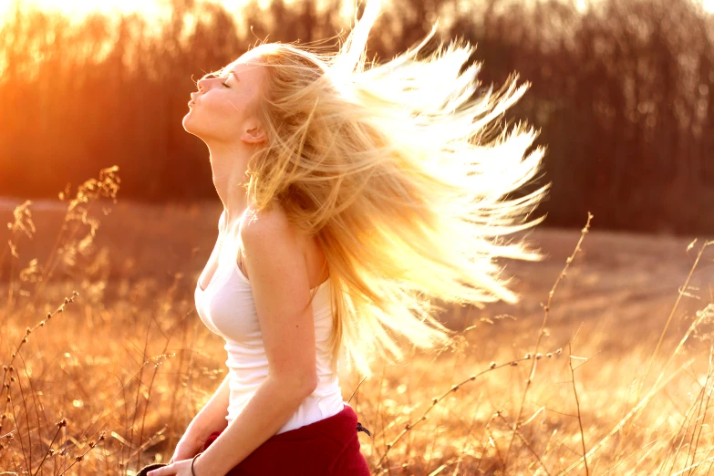 a woman is standing in the grass with her hair blowing