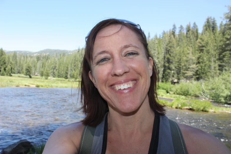 there is a smiling woman standing in front of water