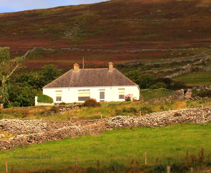 a house sits on a hill overlooking a field