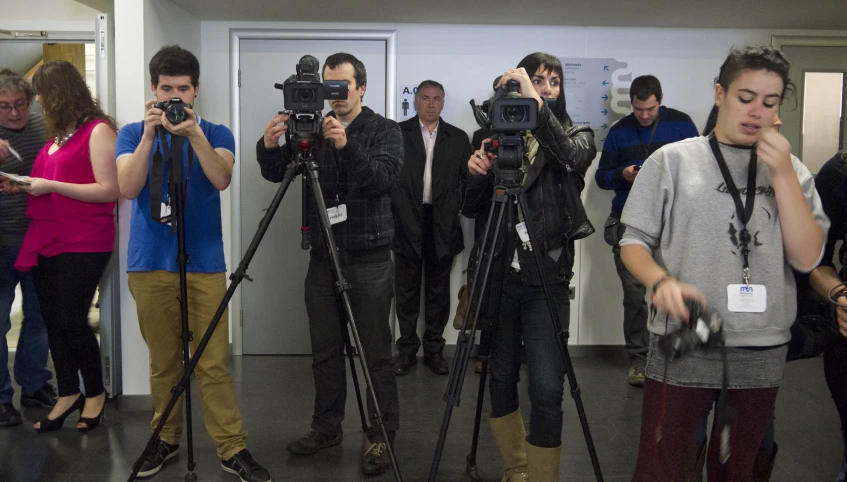 two men with cameramen taking pictures while people watch